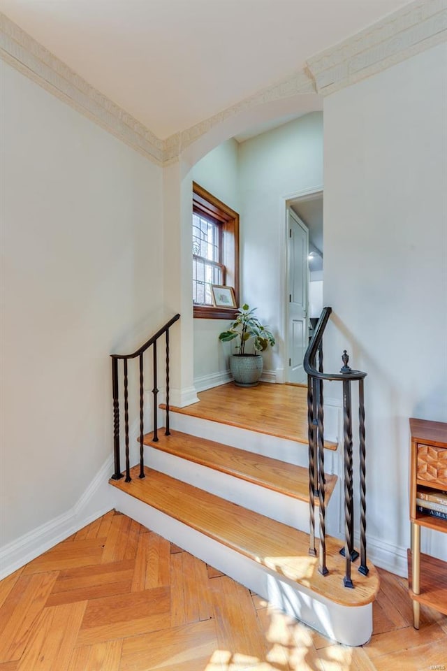 stairway featuring arched walkways and baseboards