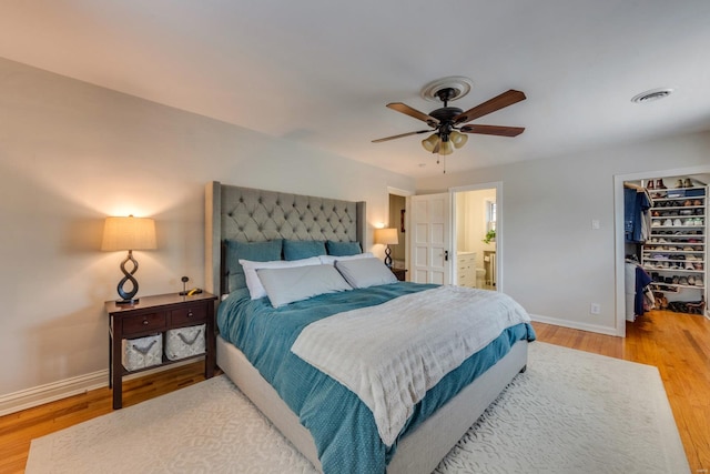 bedroom featuring visible vents, ensuite bath, light wood-style floors, baseboards, and a spacious closet
