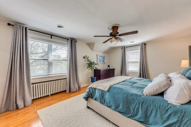 bedroom featuring wood finished floors, a ceiling fan, radiator heating unit, and visible vents