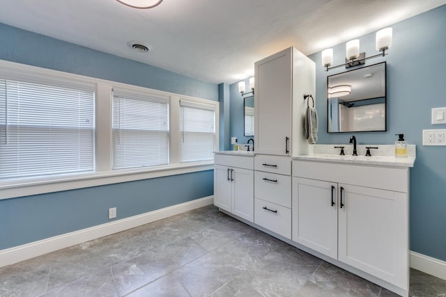 bathroom featuring double vanity, baseboards, visible vents, and a sink