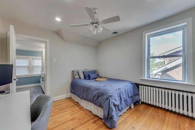 bedroom with light wood-style floors, a ceiling fan, vaulted ceiling, baseboards, and radiator heating unit