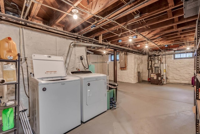 washroom with laundry area, washer and clothes dryer, a heating unit, and electric panel