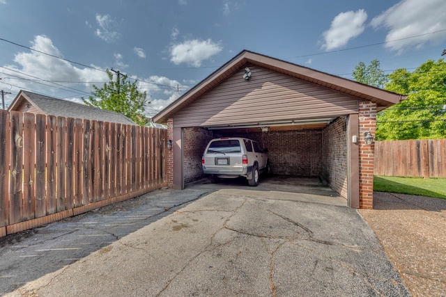 view of parking with a detached garage and fence