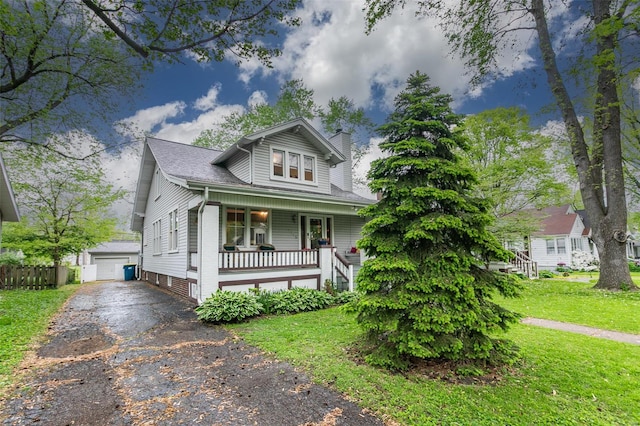 bungalow-style house featuring a front lawn, fence, covered porch, a chimney, and an outbuilding