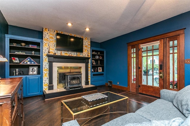 living room featuring dark wood-style flooring, a textured ceiling, built in features, a wood stove, and recessed lighting