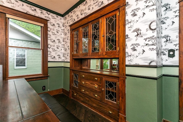 interior space with baseboards, ornamental molding, wainscoting, and wallpapered walls