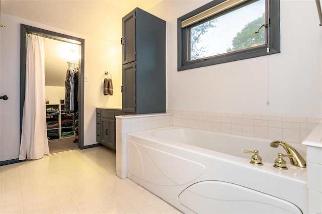 full bath featuring tile patterned floors, a garden tub, and vanity