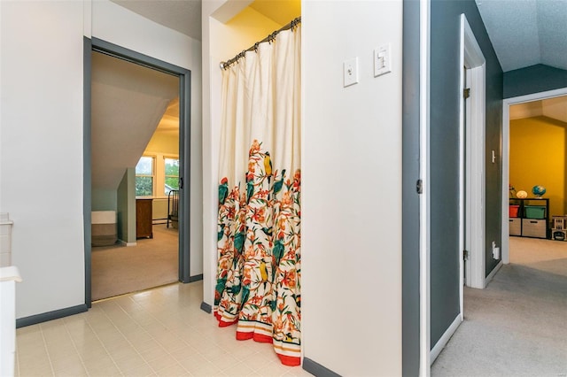 hallway with light colored carpet, a baseboard radiator, baseboards, and lofted ceiling