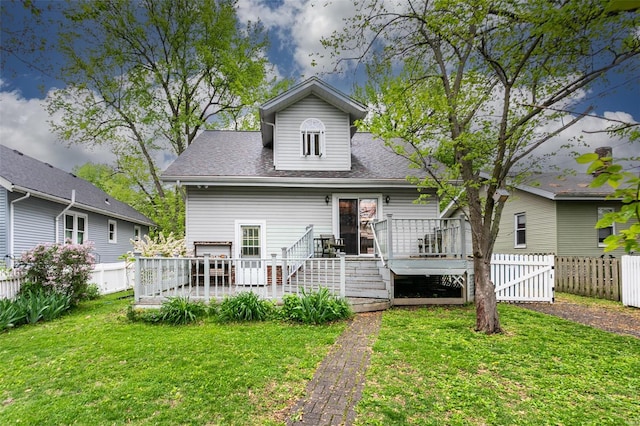 rear view of house featuring a lawn, a fenced backyard, roof with shingles, and a deck