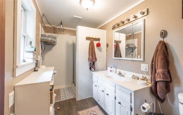 bathroom featuring a stall shower, wood finished floors, vanity, and ornamental molding