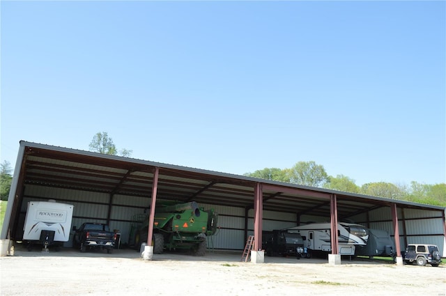 view of parking / parking lot featuring a pole building, driveway, and a detached carport