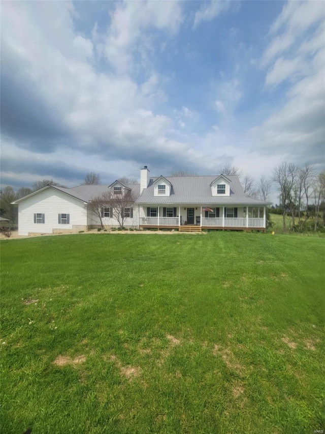 view of front of home featuring a chimney, metal roof, a front yard, and a porch