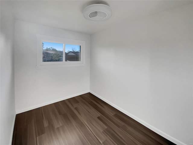 empty room with baseboards and dark wood-type flooring