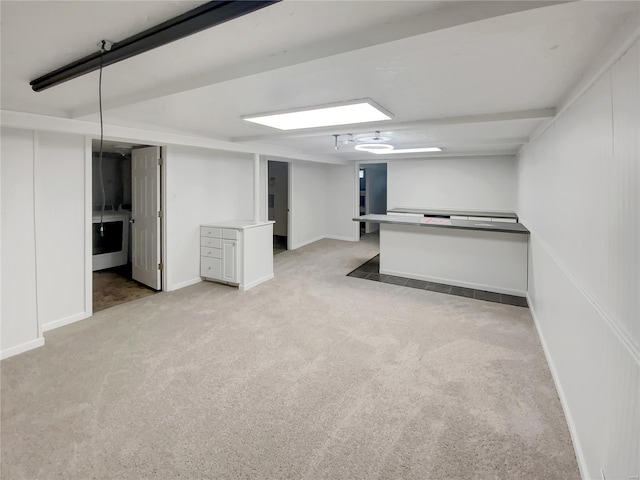 finished below grade area featuring baseboards and light carpet