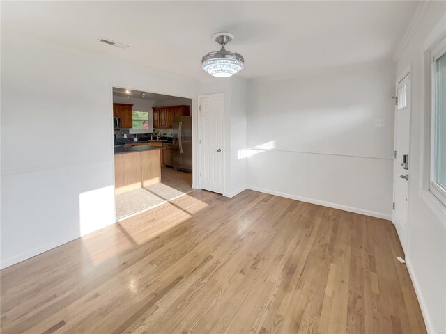 unfurnished dining area with light wood-style floors, baseboards, and visible vents