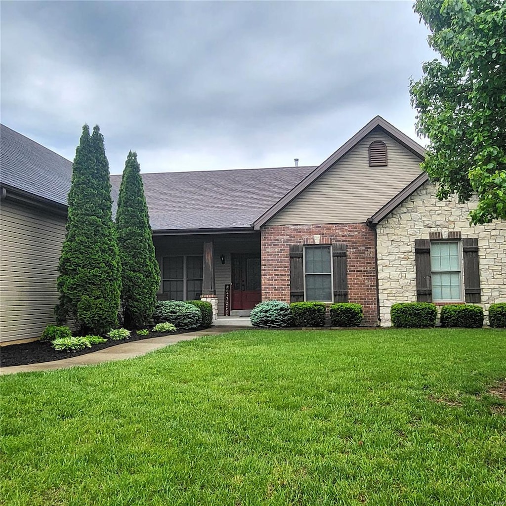 single story home with roof with shingles, a front lawn, and stone siding