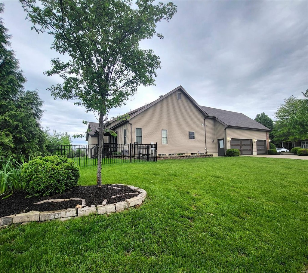 view of side of property with fence, an attached garage, a yard, and driveway