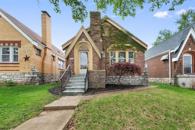 tudor home with a front lawn and brick siding