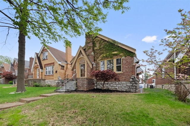 rear view of house featuring a yard and brick siding