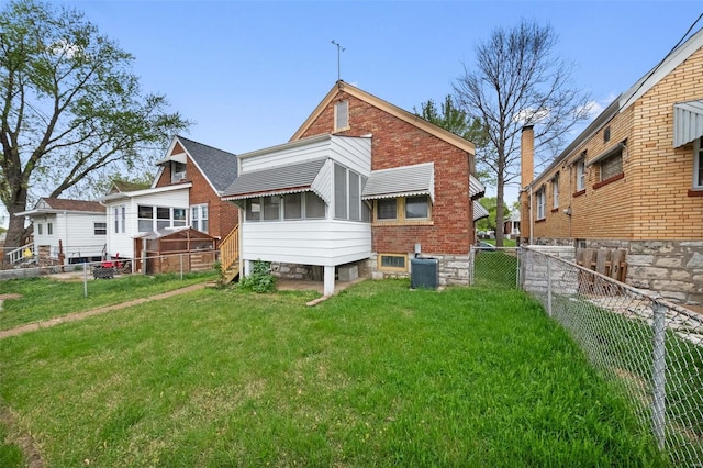 rear view of property with a yard, brick siding, and a fenced backyard