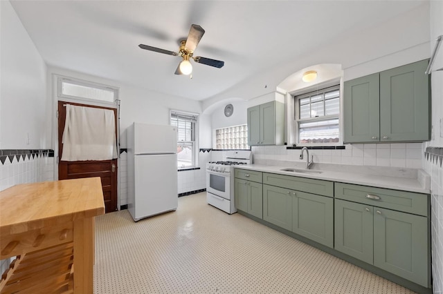 kitchen featuring a sink, tile walls, green cabinets, and white appliances