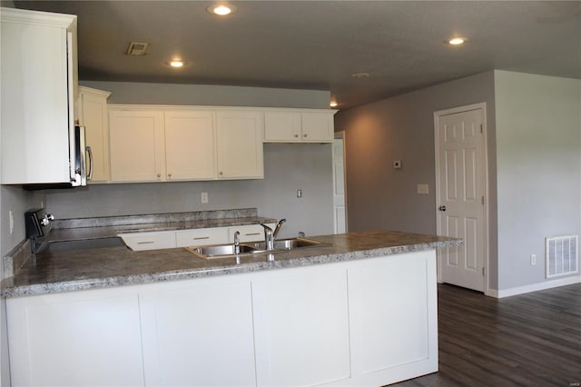 kitchen with a sink, a peninsula, recessed lighting, dark wood-type flooring, and visible vents