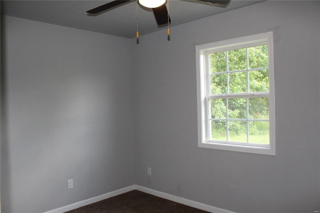 unfurnished room featuring baseboards, ceiling fan, and dark colored carpet