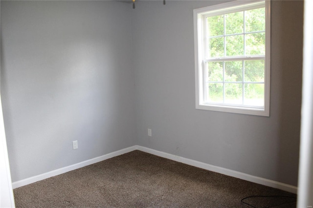 unfurnished room featuring baseboards and dark colored carpet