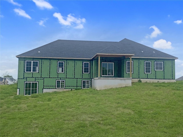 rear view of house featuring a shingled roof and a yard