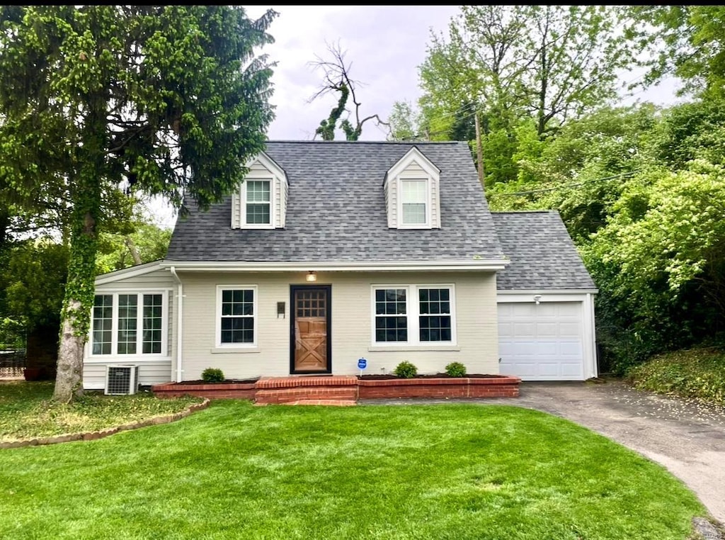 cape cod home featuring roof with shingles, an attached garage, driveway, and a front yard
