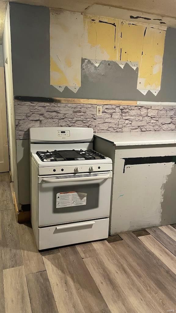 kitchen featuring light countertops, white range with gas stovetop, and light wood-type flooring