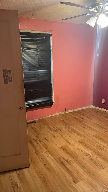 spare room with baseboards, a textured ceiling, ceiling fan, and wood finished floors