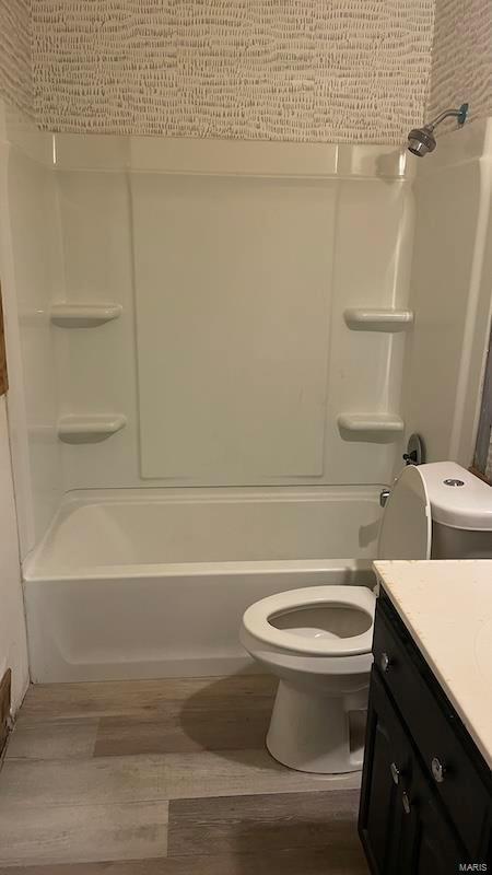 bathroom featuring tub / shower combination, wood finished floors, toilet, and vanity