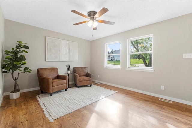 sitting room with visible vents, a ceiling fan, baseboards, and wood finished floors