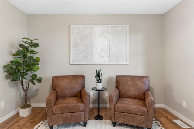 living area featuring visible vents, baseboards, and wood finished floors