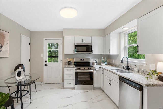 kitchen with a sink, marble finish floor, appliances with stainless steel finishes, and white cabinetry