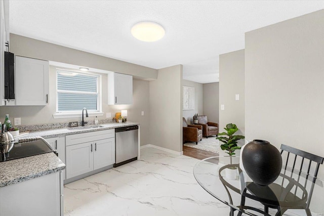 kitchen featuring stainless steel dishwasher, a sink, light stone counters, white cabinets, and marble finish floor