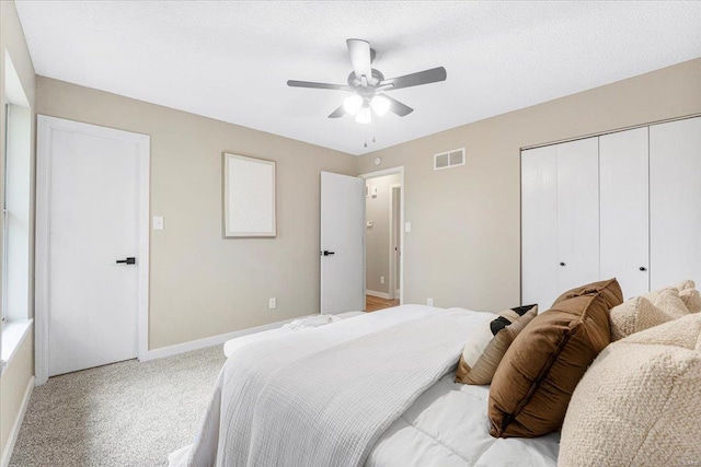 bedroom featuring ceiling fan, light colored carpet, visible vents, baseboards, and a closet