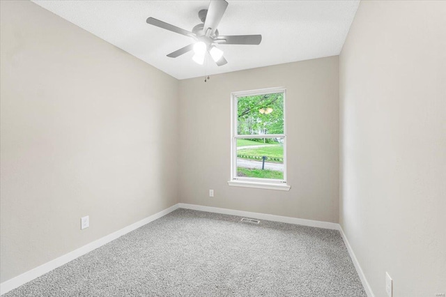 empty room with carpet floors, baseboards, ceiling fan, and visible vents