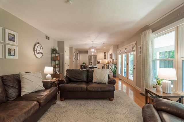 living area featuring visible vents, light wood-style floors, and a chandelier