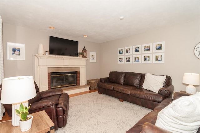 living room with recessed lighting, a glass covered fireplace, and wood finished floors