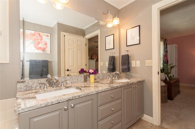 bathroom featuring a sink, baseboards, crown molding, and double vanity