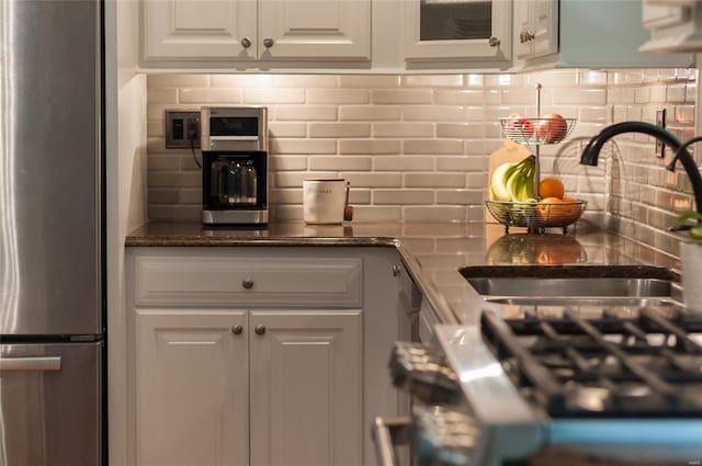 kitchen featuring backsplash, range, a sink, white cabinets, and freestanding refrigerator