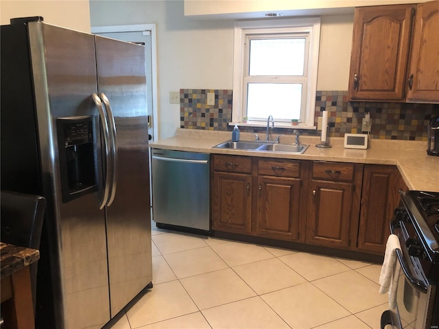 kitchen featuring decorative backsplash, light tile patterned flooring, light countertops, a sink, and appliances with stainless steel finishes