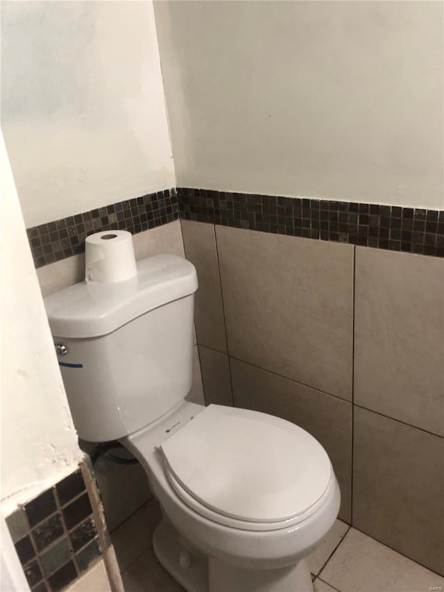 bathroom featuring tile patterned flooring, toilet, and tile walls