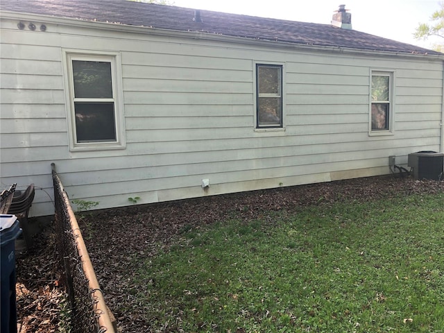 view of property exterior featuring a lawn, a chimney, roof with shingles, and central air condition unit