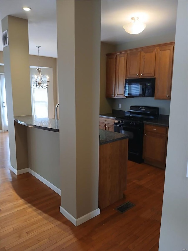 kitchen featuring baseboards, visible vents, black appliances, and light wood-type flooring