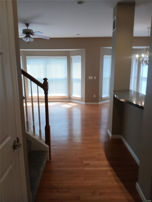 corridor featuring baseboards, stairs, wood finished floors, and visible vents