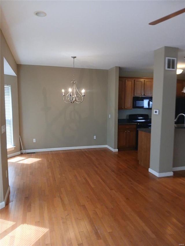kitchen with dark countertops, black microwave, baseboards, visible vents, and hardwood / wood-style flooring