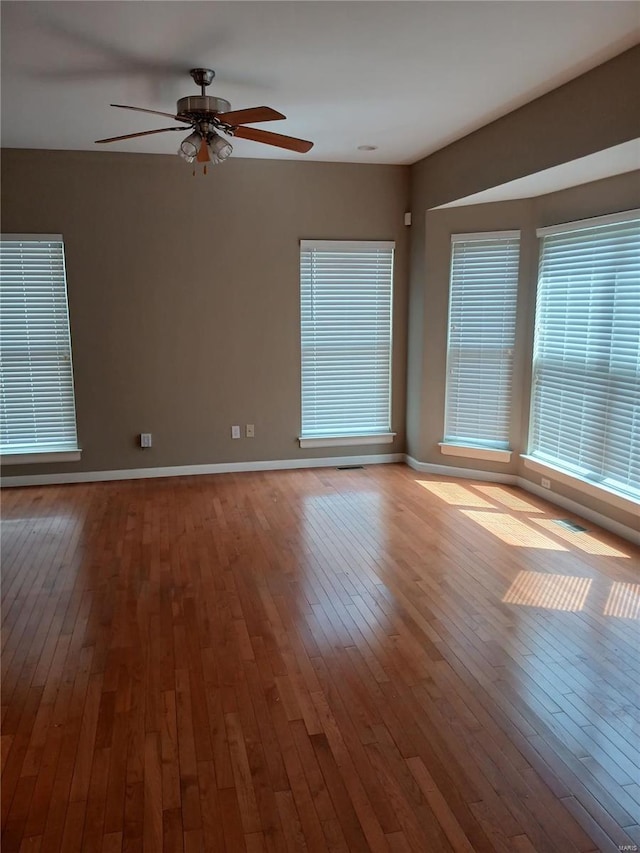 empty room with ceiling fan, baseboards, and hardwood / wood-style floors